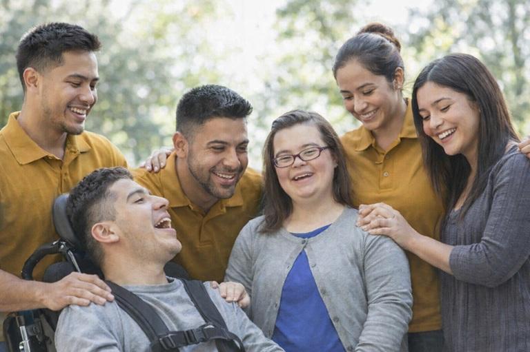 A caring support team laughing together with two young adults outdoors
